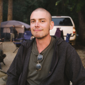 man with bald head smiling in camp setting