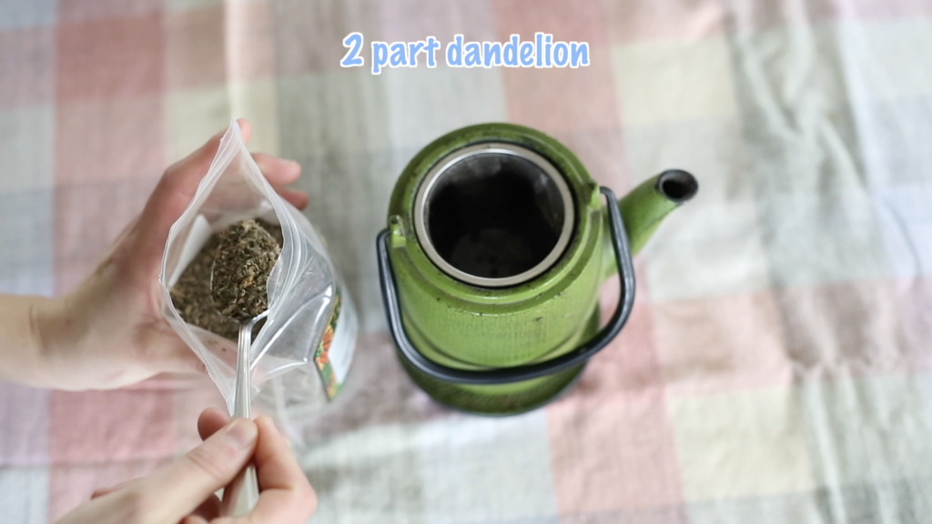 scooping dandelion leaf into tea pot sift