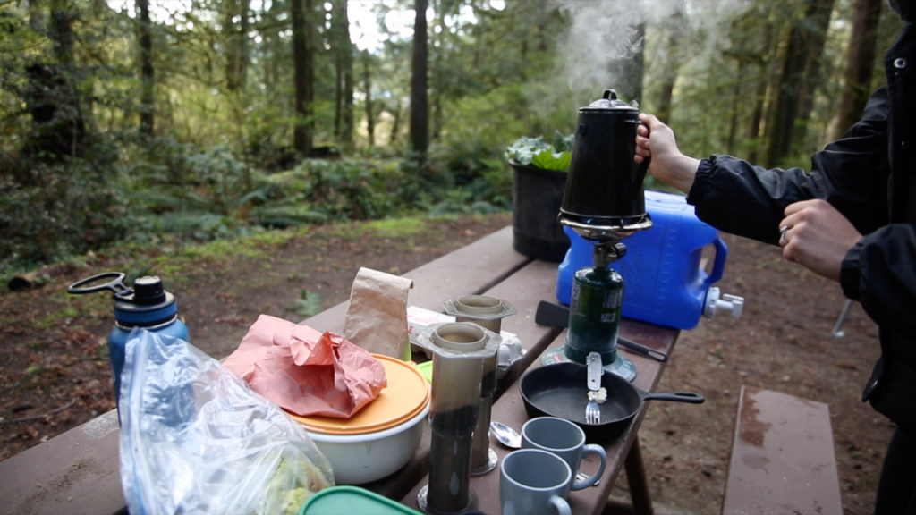 camping table with gas burner, kettle aero press coffee, mugs, water bottle and food
