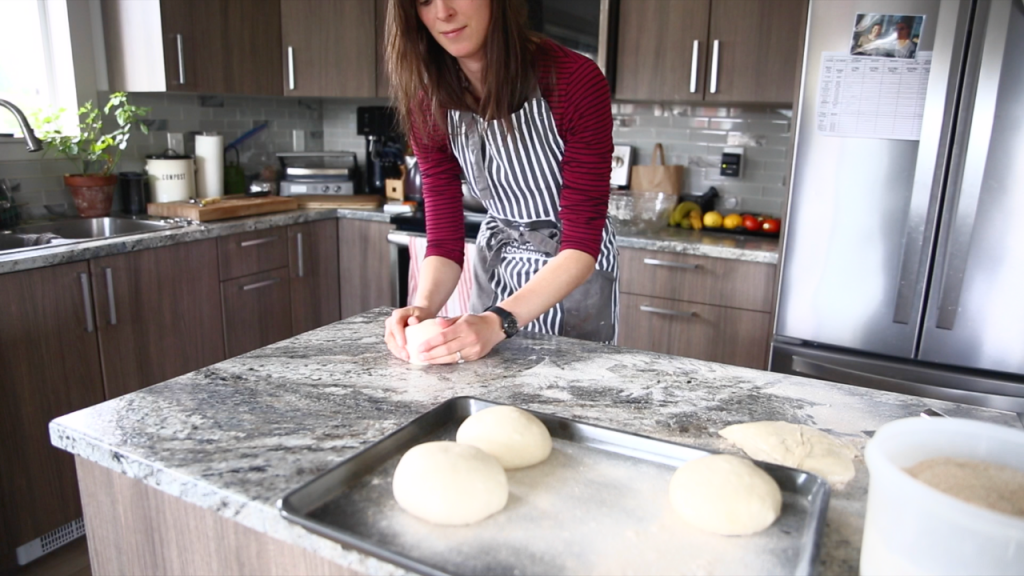 woman shaping dough into balls on counter