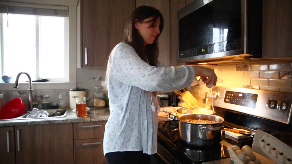 woman in blue shirt cracking eggs into mince dinner